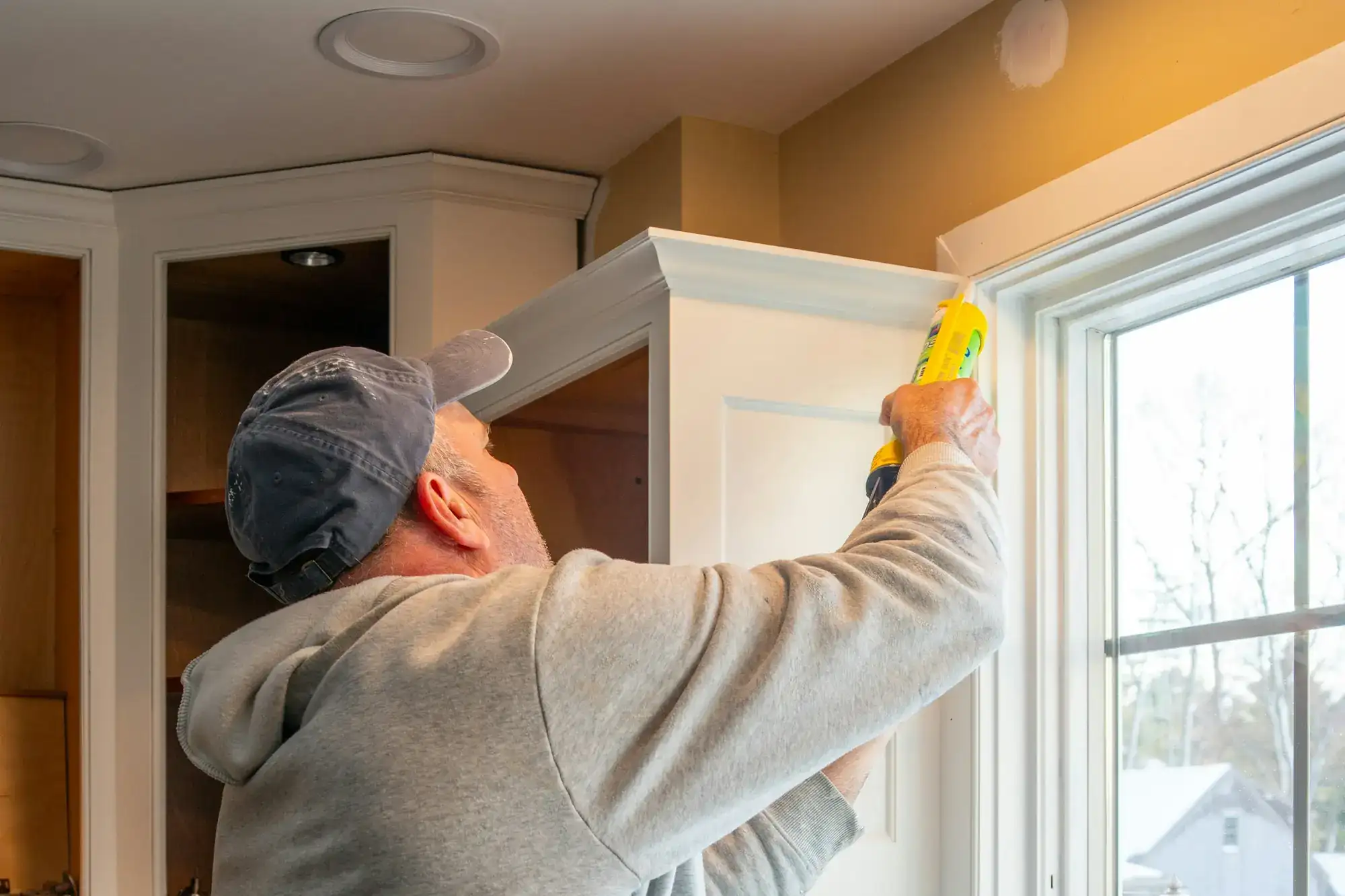 A worker caulking the trim on a new kitchen window (stock photo)
