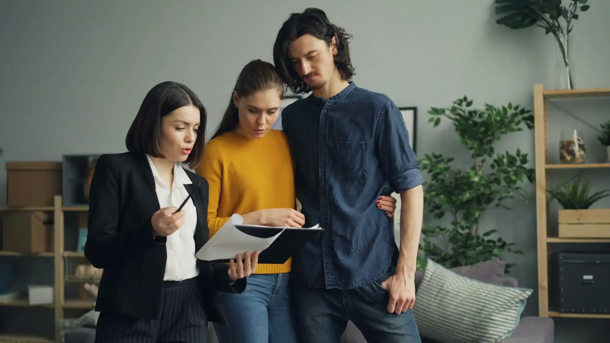 An agent and two clients reading a printed page together (stock photo)