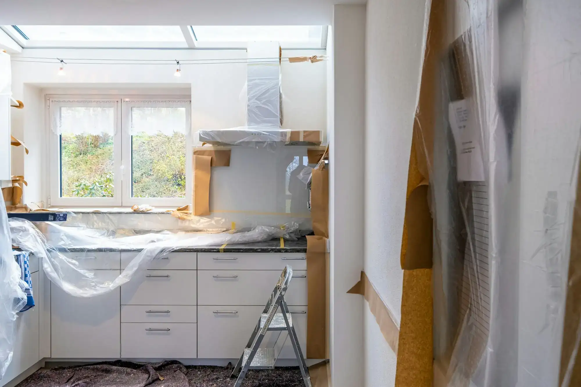 A kitchen mid-renovation with cabinets wrapped in plastic (stock photo)