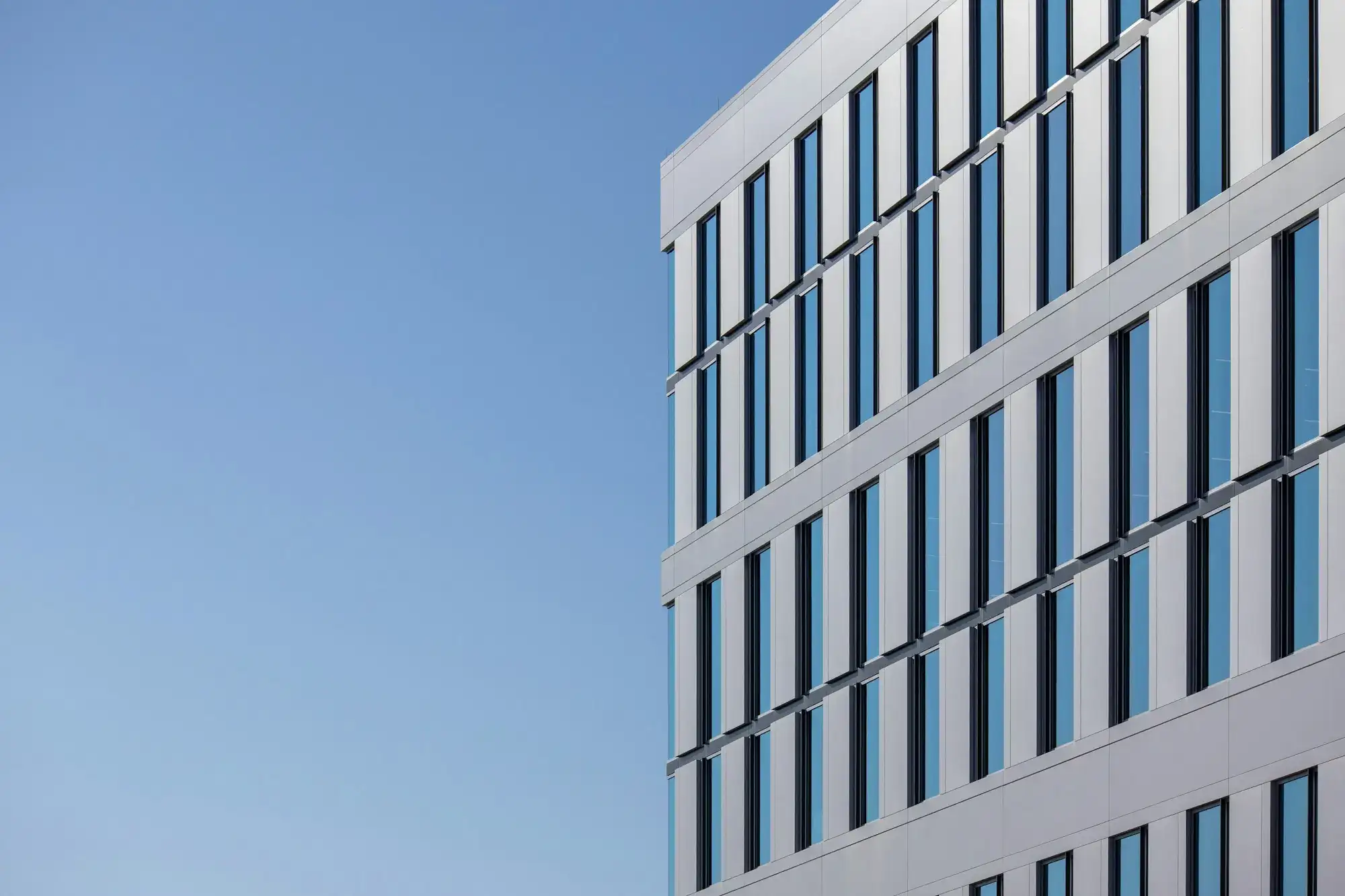 A modern white office building against a blue sky (stock photo)